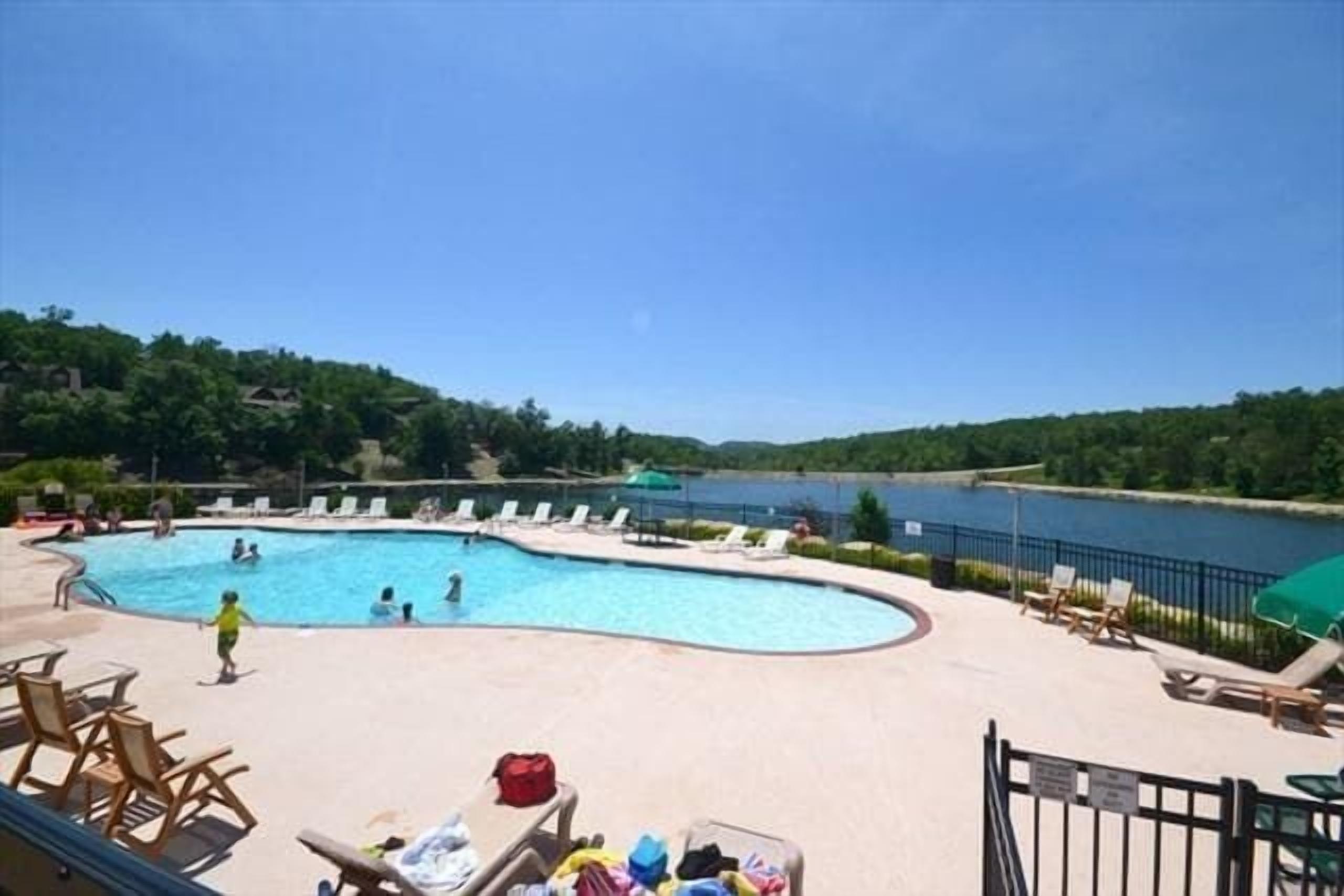 A swimming pool with lounge chairs and a view of a lake.