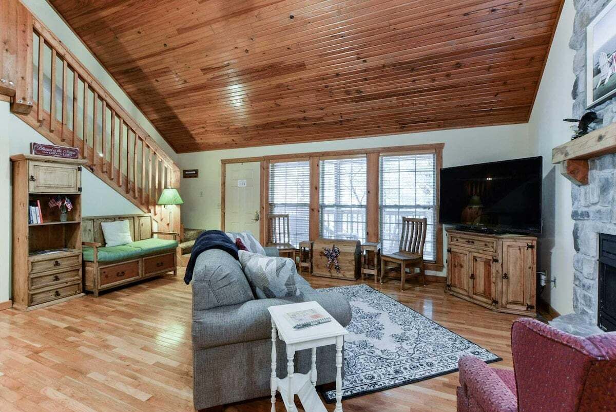 Ein geräumiges Wohnzimmer mit Holzbalkendecke, Kamin, Fernseher und einer gemütlichen Sitzecke.