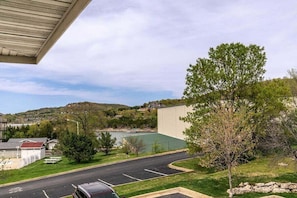 A parking lot with a building, a tree, and a view of a lake and hills. - Table Rock Condo_Huge Deck_New Flooring_Private_Free Tickets (Hollister)