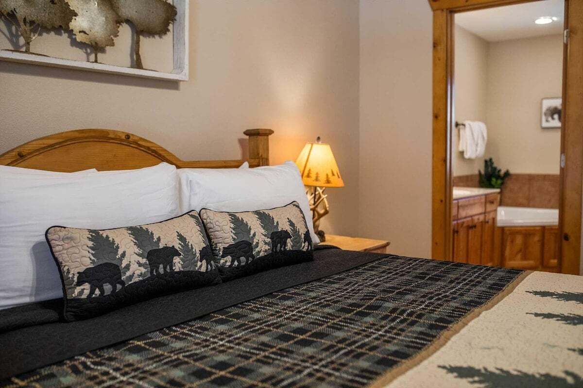 A bed with a plaid bedspread and two pillows with a wildlife print.