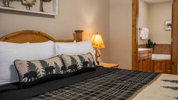 A bed with a plaid bedspread and two pillows with a wildlife print.
