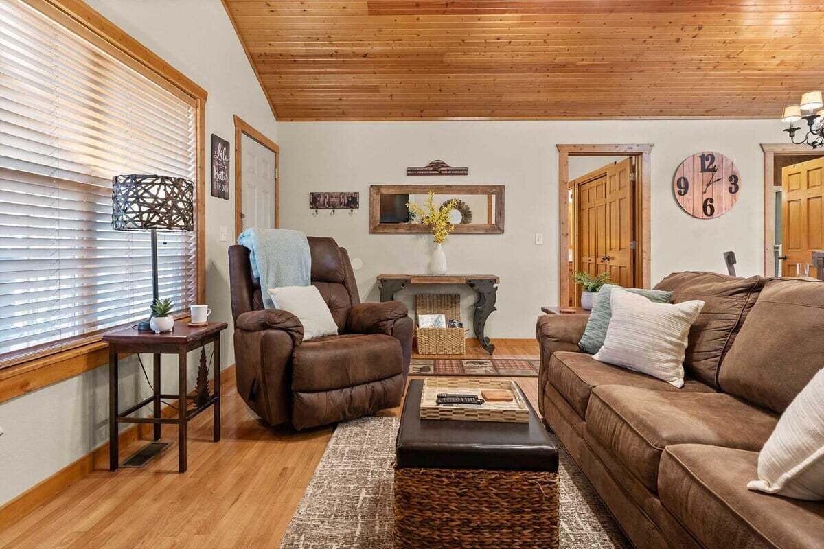 A cozy living room with a brown leather sofa, a brown recliner, a coffee table, and a fireplace.