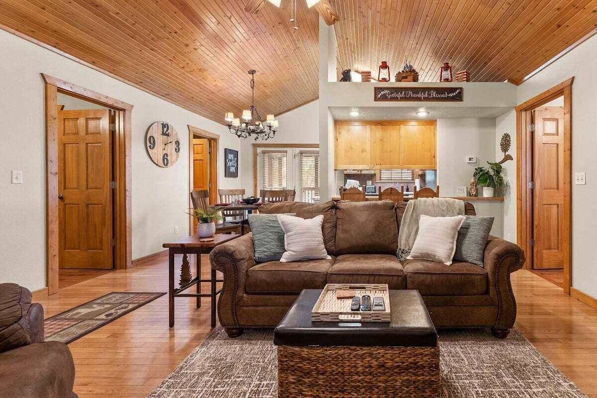 A cozy living room with a brown leather sofa, a coffee table, and a dining area with wooden cabinets.