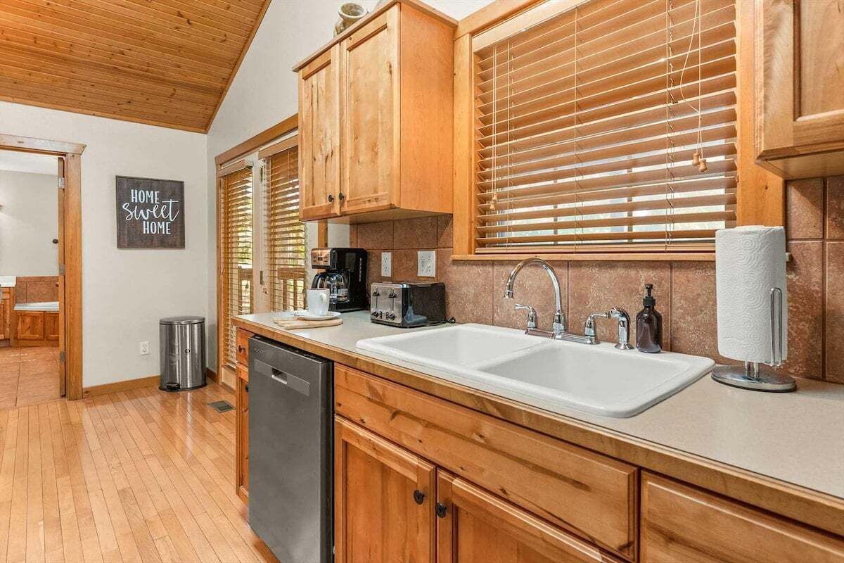 A kitchen with wooden cabinets, a double sink, and a coffee maker.