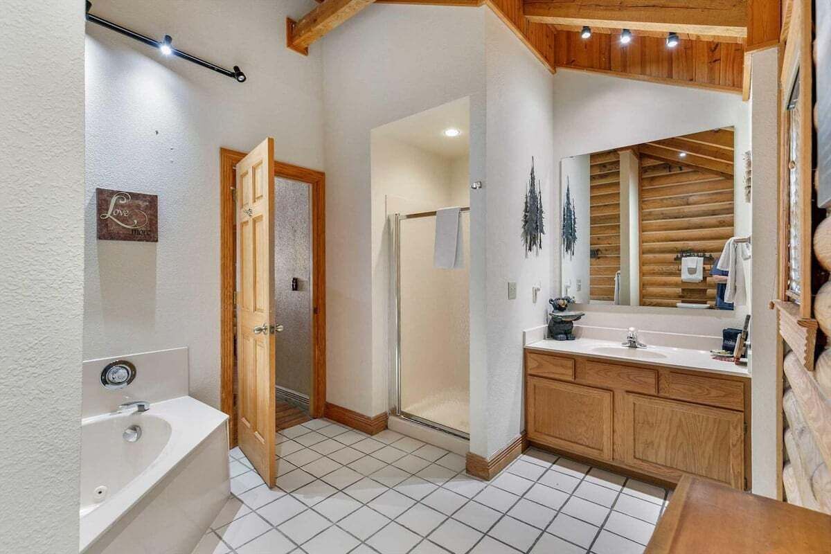 A bathroom with a bathtub, a shower, and a vanity with a mirror.