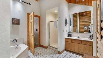 A bathroom with a bathtub, a shower, and a vanity with a mirror.
