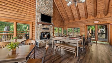 L’intérieur d’une cabane en rondins, avec une cheminée en pierre, une table à manger en bois et plusieurs coins salon.