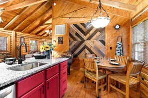 A cabin interior with a kitchen, dining area, and a large wooden wall with a chevron pattern. - Lots of Space_Multiple Amenities in Gated Community_True Log Cabin (Branson)