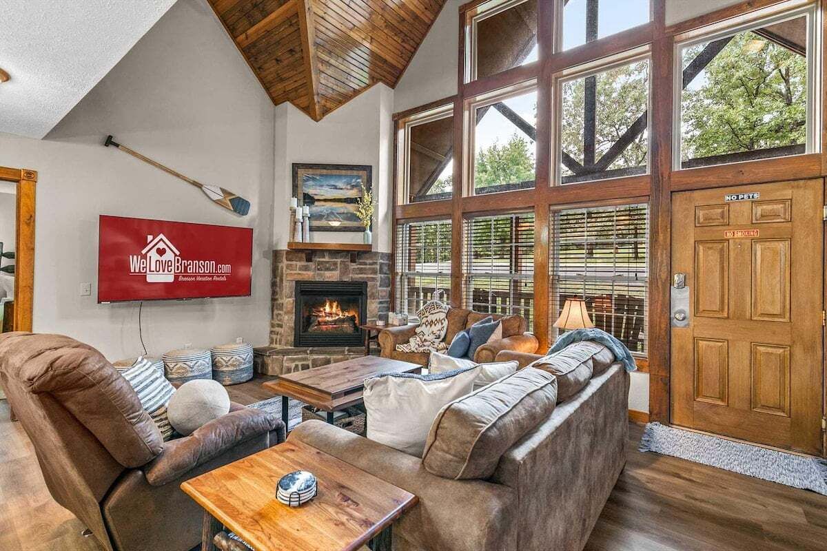 A spacious living room with a fireplace, large windows, and a sign indicating pet policy.