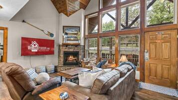 A spacious living room with a fireplace, large windows, and a sign indicating pet policy.