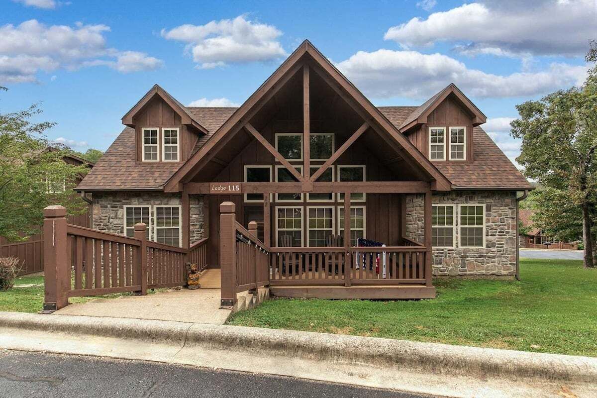 A lodge with a stone facade, a wooden deck, and a gated entrance.