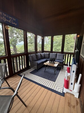 A covered outdoor seating area with a sofa, a table, and a rug. - Updated Stonebridge Lodge, Log Beds, Deck with TV, Free Daily Attraction Tickets (Branson West)