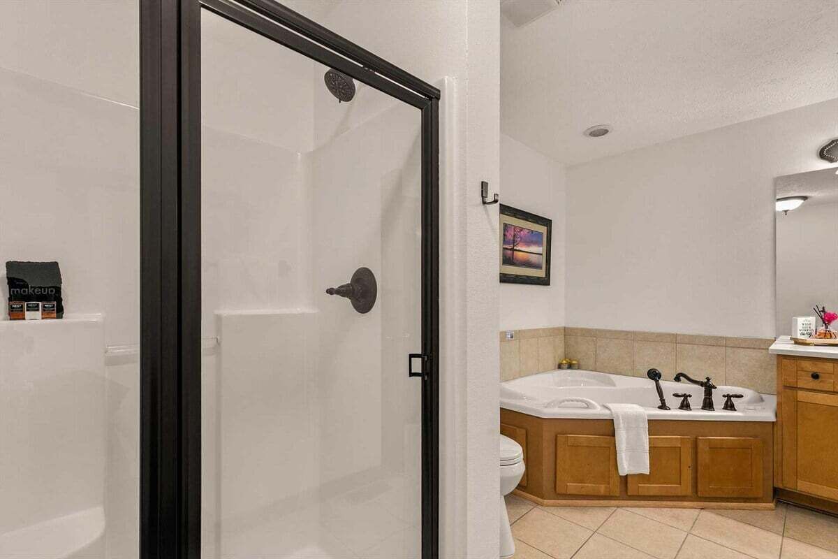 A bathroom with a glass-enclosed shower, a bathtub, and wooden cabinets.