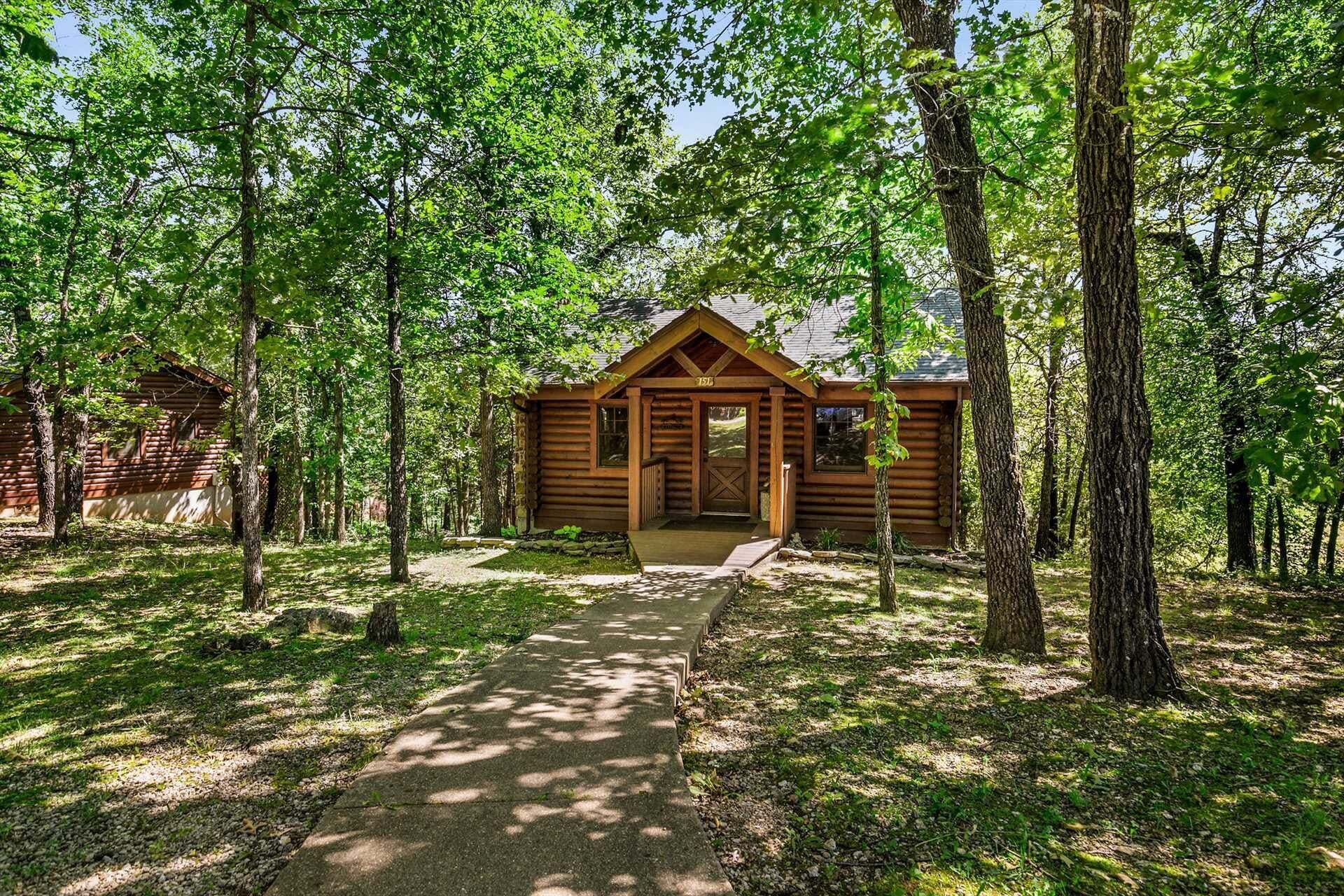 Une cabane dotée d’une véranda, entourée d’arbres.