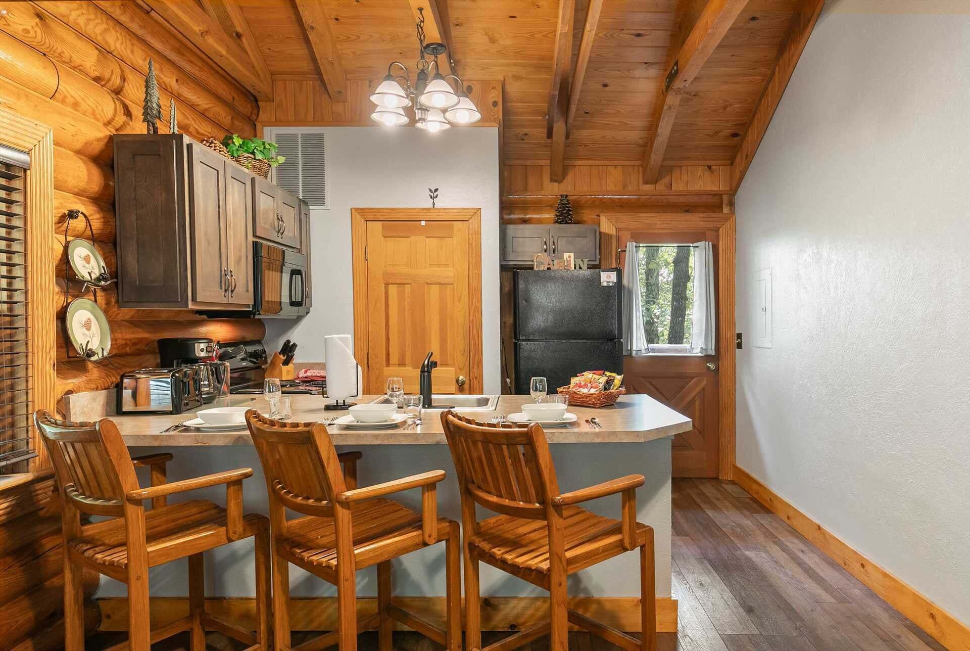 Una cocina estilo cabaña con armarios de madera, una isla central con taburetes y un refrigerador.