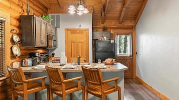 Una cocina estilo cabaña con armarios de madera, una isla central con taburetes y un refrigerador.