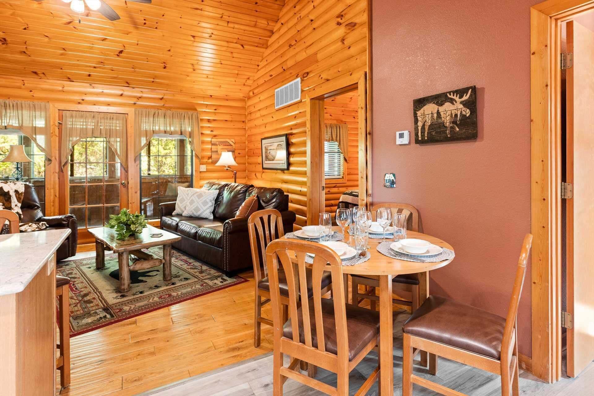 L’intérieur d’une cabane en rondins comprend un coin repas, un salon avec un canapé en cuir et une cheminée.