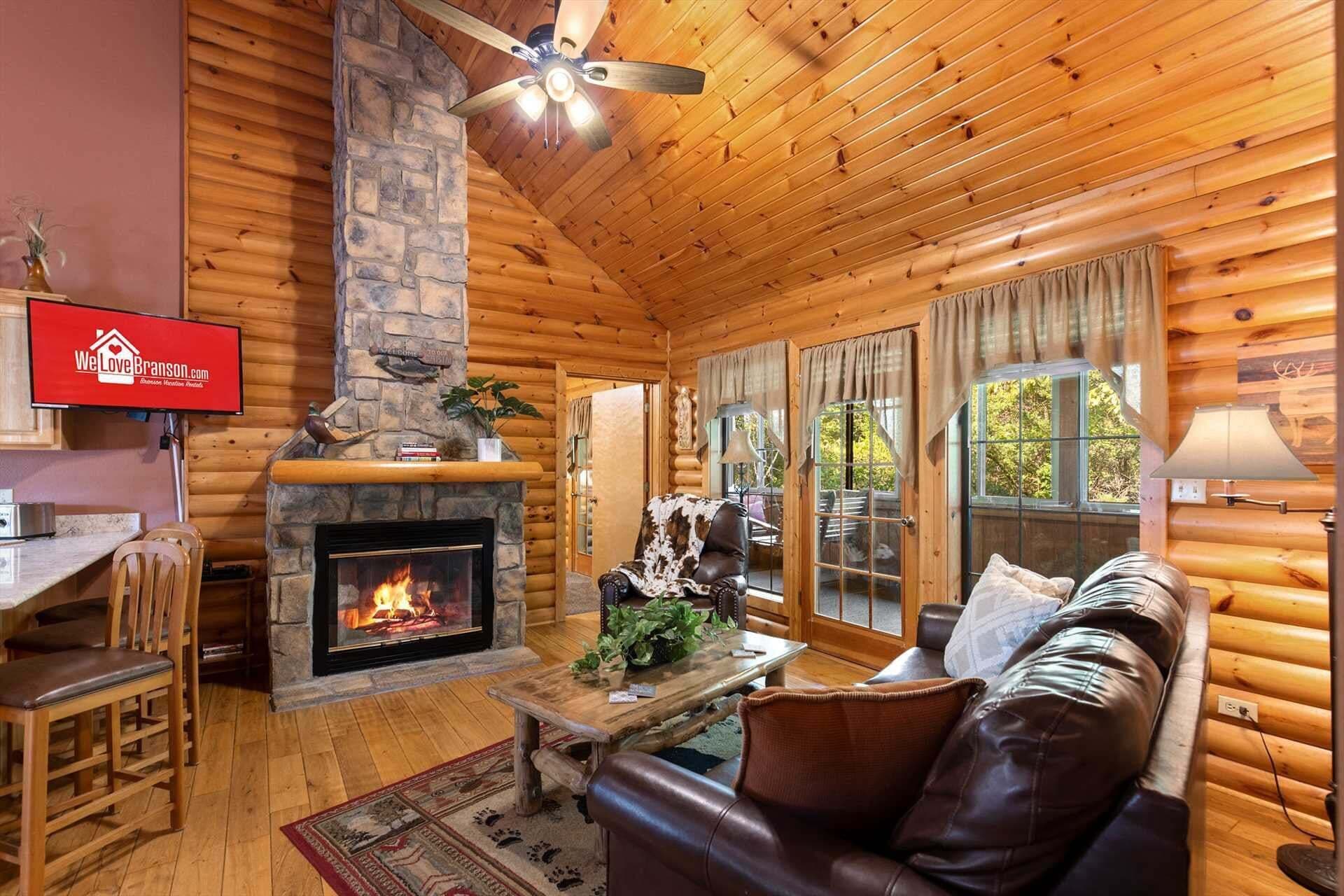 Interior d'una cabana de fusta amb una llar de pedra, mobles de fusta i un televisor que mostra 'We Love Branson.com'.