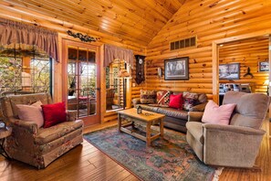 A log cabin interior with a wooden floor, a sofa set, a coffee table, and a fireplace.