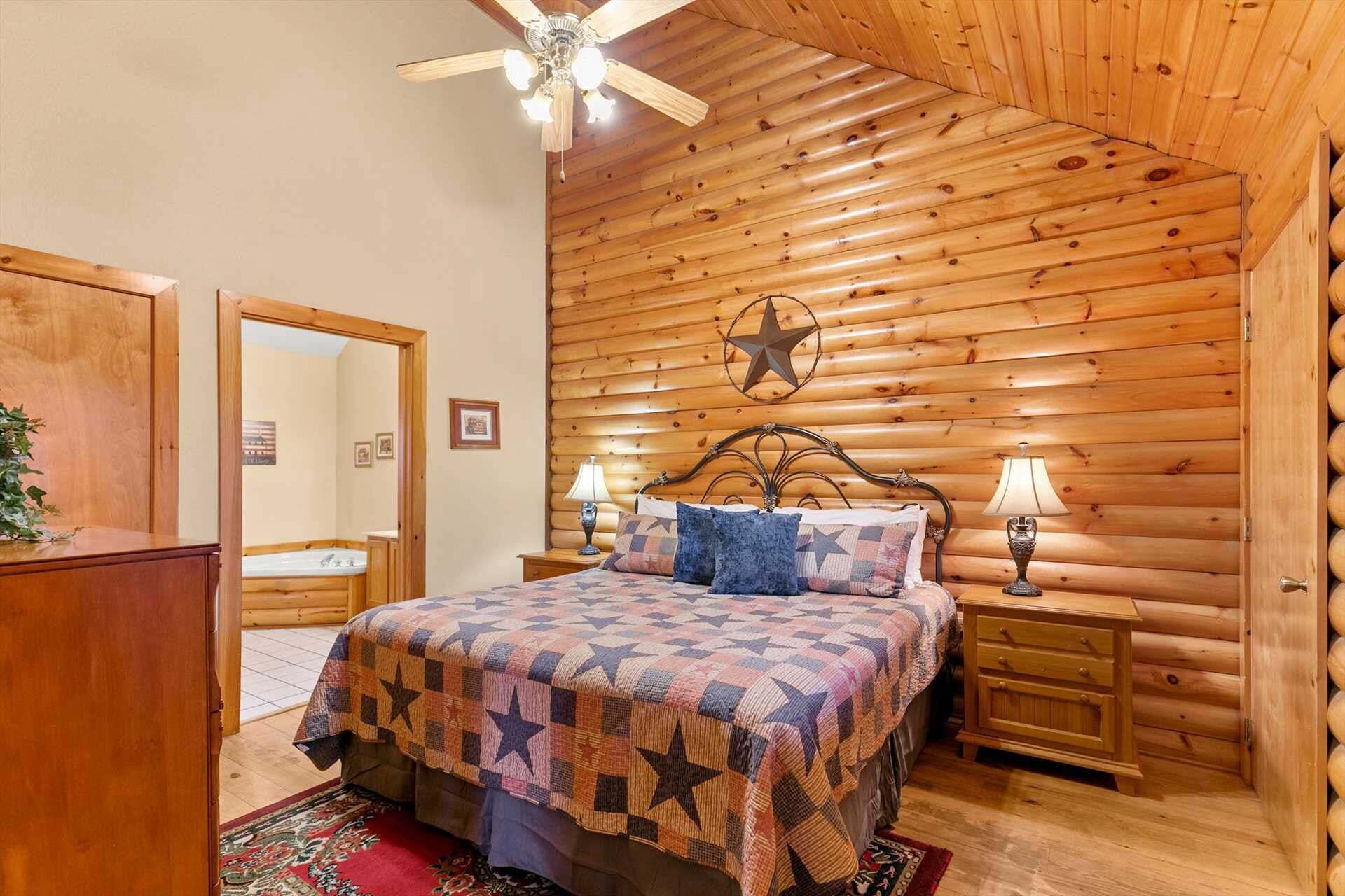 A log cabin-style bedroom with a bed, two bedside tables, a ceiling fan, and a star decoration on the wall.