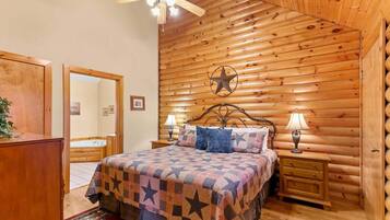 A log cabin-style bedroom with a bed, two bedside tables, a ceiling fan, and a star decoration on the wall.