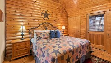 A wooden cabin bedroom with a bed, two bedside tables with lamps, a star decoration, and a window with blinds.