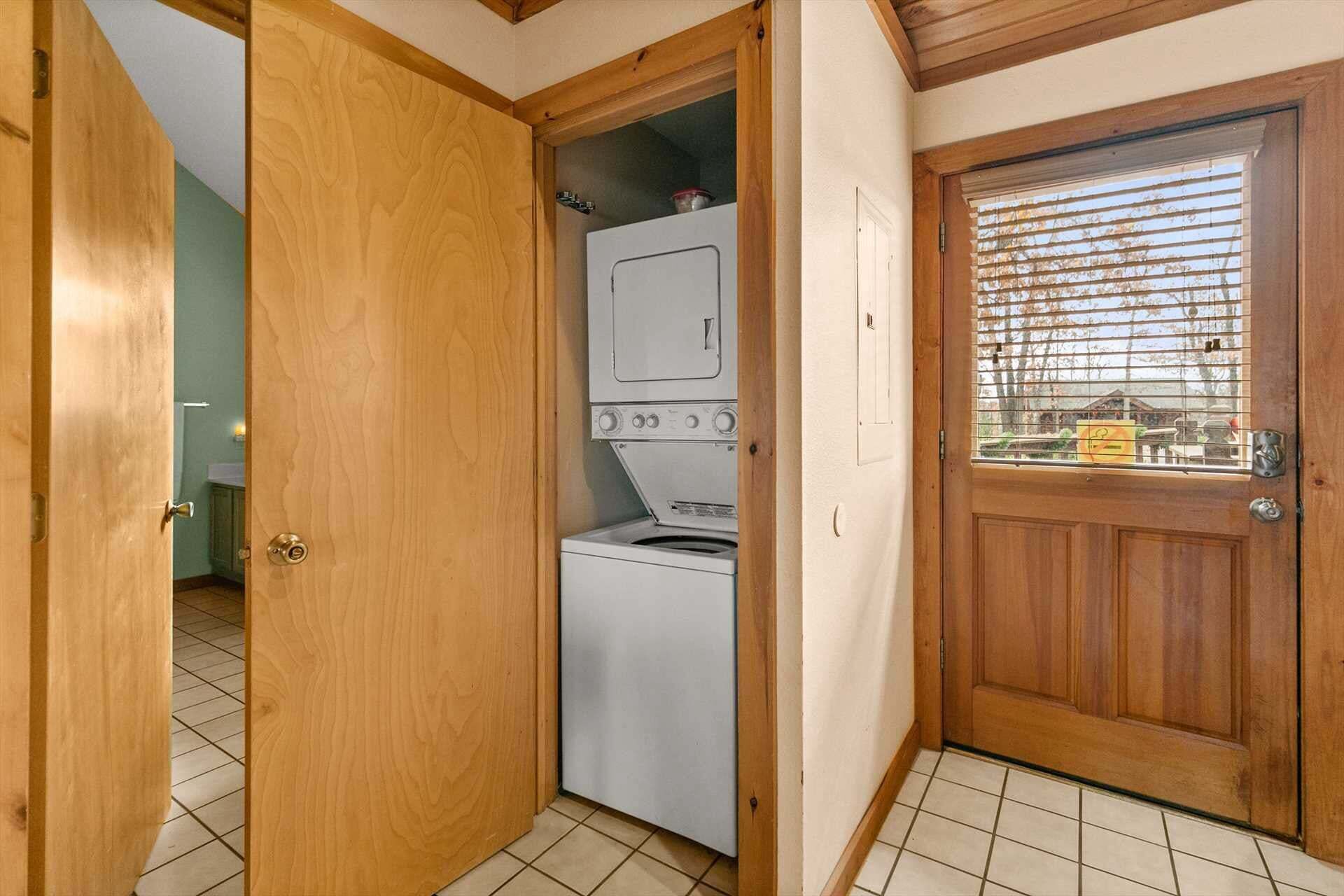 Un lavadero con lavadora y secadora, puertas de madera y piso de baldosas.