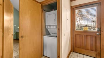 Un lavadero con lavadora y secadora, puertas de madera y piso de baldosas.