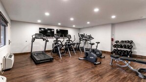 Et fitnesscenter med løbebånd, crosstrainere og bænkpres.