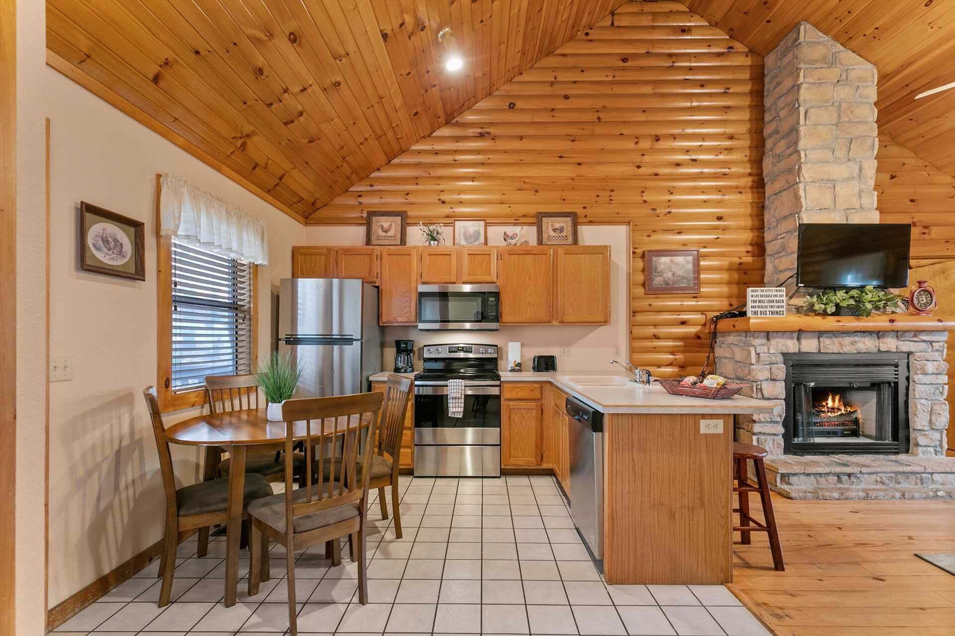 A kitchen with wooden cabinets, a central island, a stone fireplace, and a television mounted above it.