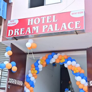 A hotel entrance with a sign for 'Hotel Dream Palace' and a contact number.