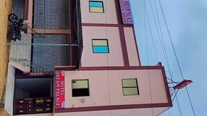 A multi-story building with a sign for 'HOTEL DREAM PALACE' and a sign for 'ROOMS' indicating available accommodations. - Hotel Dream Palace (Luni)