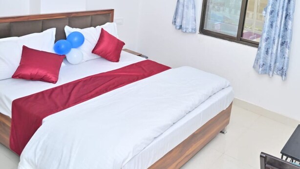 A hotel room with a bed, a window with curtains, and a small table. - Hotel Dream Palace (Luni)