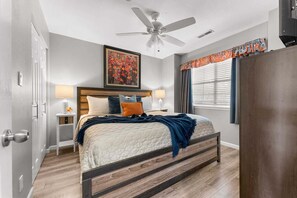 A bedroom with a bed, bedside lamps, a ceiling fan, a painting, and a window with curtains. - Right Next to Silver Dollar City, Outdoor Pool, Luxury Furnishings-Free Tickets (Branson)