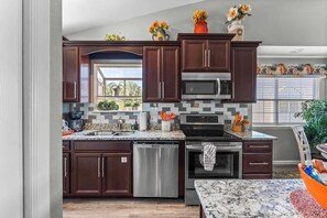 A modern kitchen with dark wood cabinets, stainless steel appliances, and a granite countertop. - Right Next to Silver Dollar City, Outdoor Pool, Luxury Furnishings-Free Tickets (Branson)