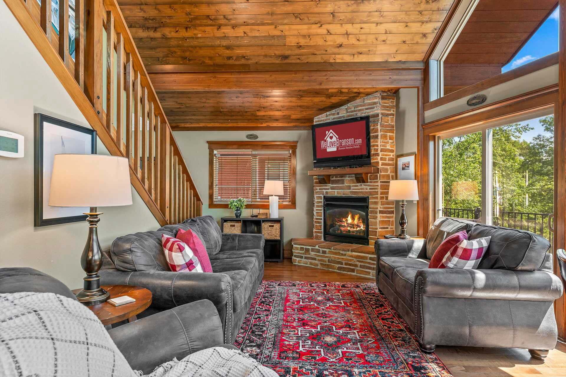 A cozy living room with leather sofas, a fireplace, and a large window.