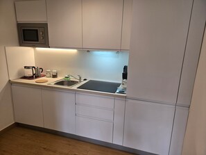 Una cocina moderna con microondas integrado, hervidor de agua, cafetera y bloque de cuchillos.