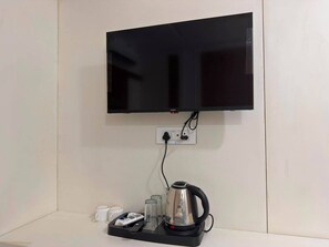 A flat-screen TV mounted on a wall with a power outlet below it. - Ramayana By Yland (Orchha)