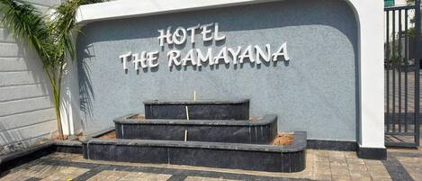 A hotel entrance with a sign reading 'HOTEL THE RAMAYANA' and a set of steps leading up to it.