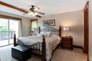 A bedroom with a bed, a nightstand, a lamp, a ceiling fan, and a window. - Two Log Cabins in One Right on Table Rock Lake-Free Daily Attraction Tickets (Branson)