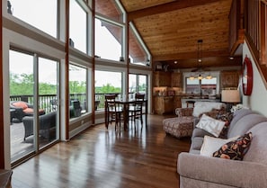 A spacious living area with a large dining table, a sofa, and a kitchen in the background. - Two Log Cabins in One Right on Table Rock Lake-Free Daily Attraction Tickets (Branson)