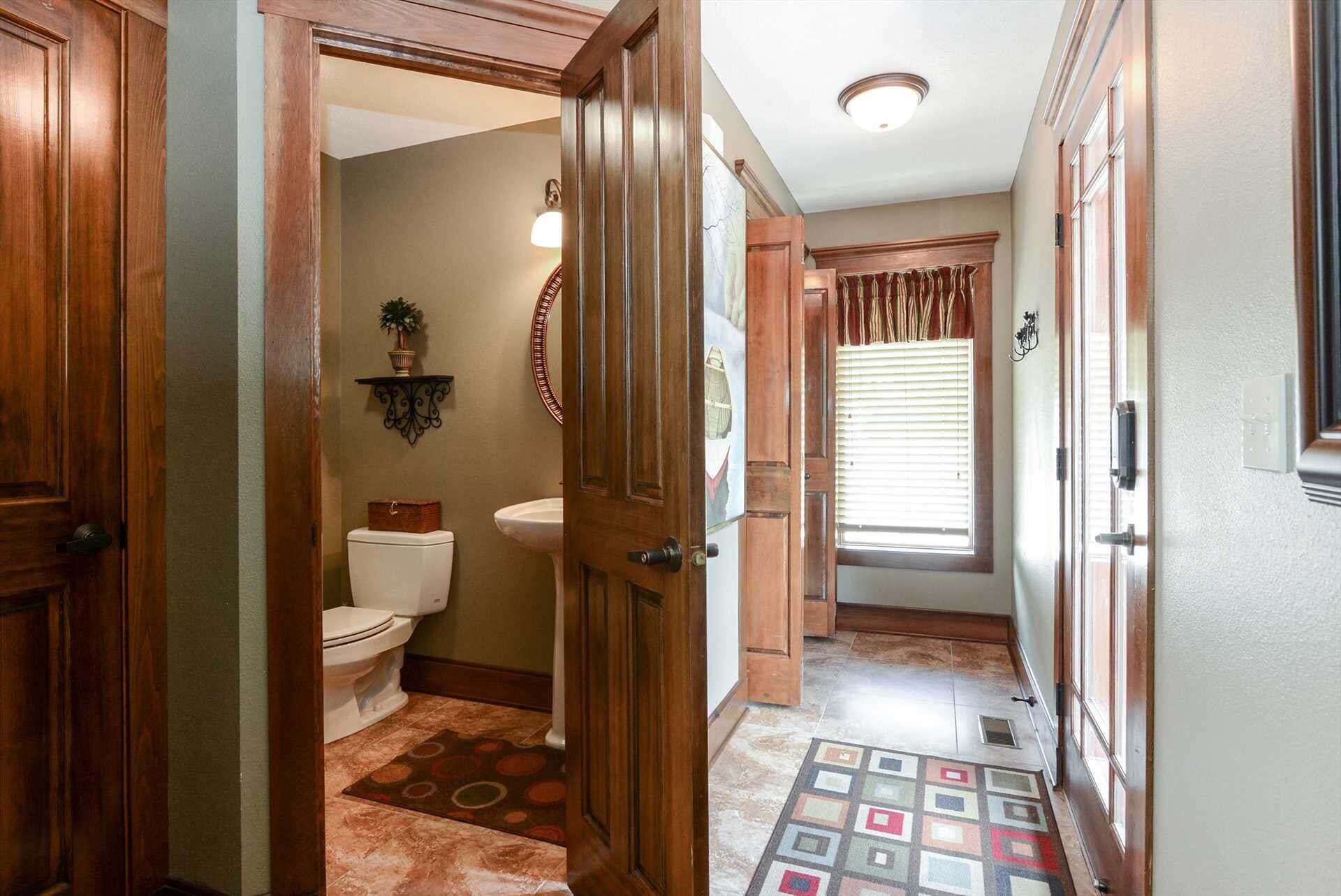 A hallway with wooden doors, a white toilet, a sink, and a patterned rug.