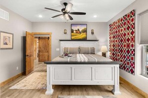 A bedroom with a bed, a ceiling fan, a painting, a wall art piece, and a window. - Amazing Lake Views_Private Hot Tub_Community Amenities_Free Daily Attraction Tickets (Branson)