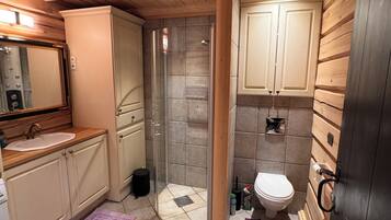 A bathroom with a wooden ceiling, a glass shower enclosure, a sink, and a toilet.