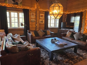 A cozy log cabin interior with a sofa set, a coffee table, and a television.