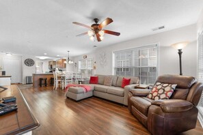 A spacious living room with a sofa, a recliner, a dining area, and a kitchen in the background. - StoneBridge Condo Near SDC w Onsite Golf Course_Screen Porch_Free Attraction Tickets (Branson West)