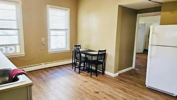A kitchen with a dining table and chairs, a refrigerator, and a window with blinds.