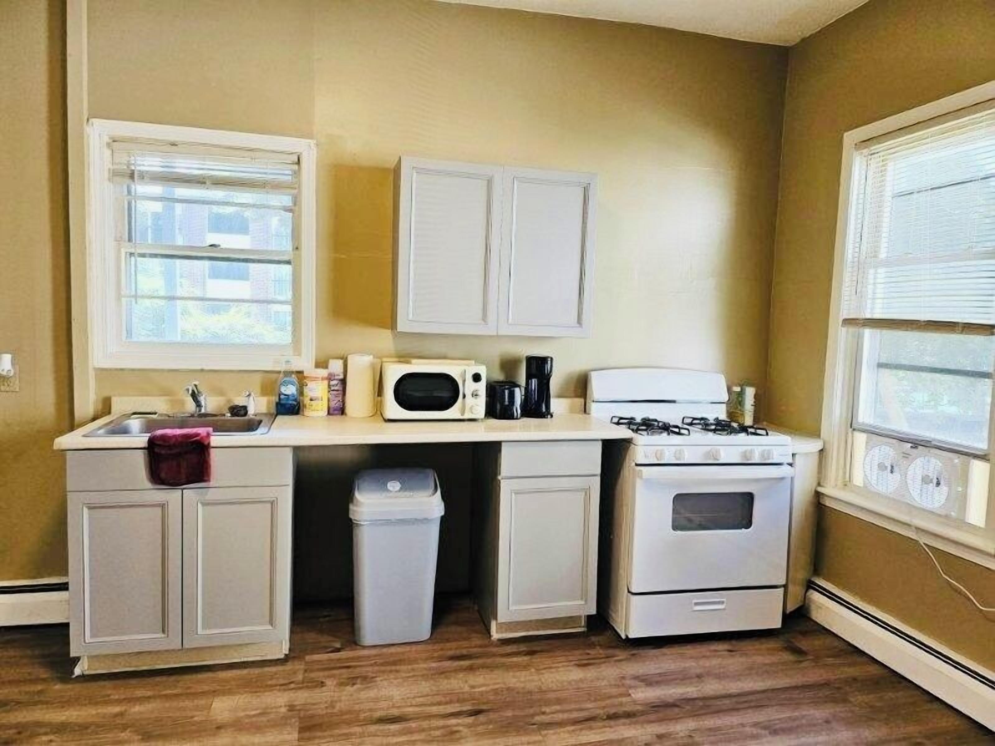 Une cuisine de taille réduite équipée d’un évier, d’un four à micro-ondes, d’une cuisinière et de placards.