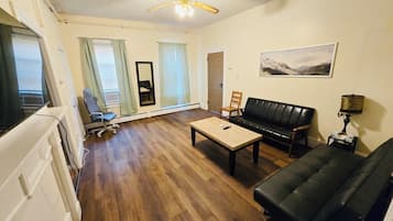 Un salon avec un canapé, une table basse, un téléviseur et un ventilateur de plafond.