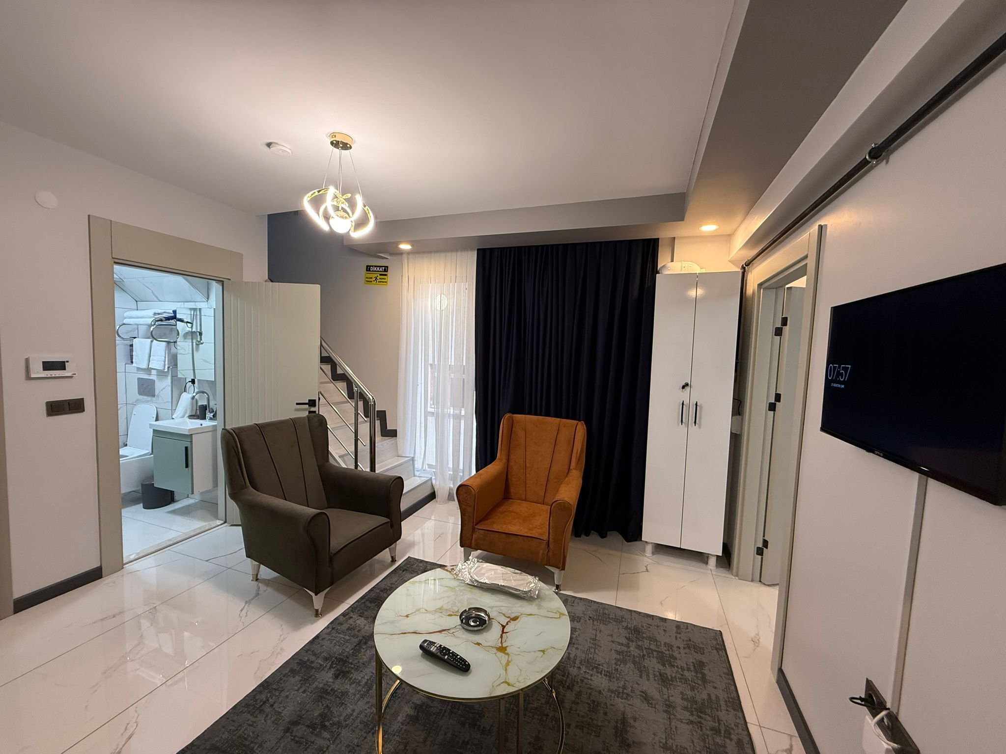 Una sala de estar moderna con sofá, sillón, mesa de centro y televisor.